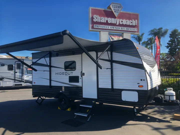 Modern Hideout travel trailer with awning extended, an ideal RV rental option from Sharemycoach.com.. Keystone Hideout 2020