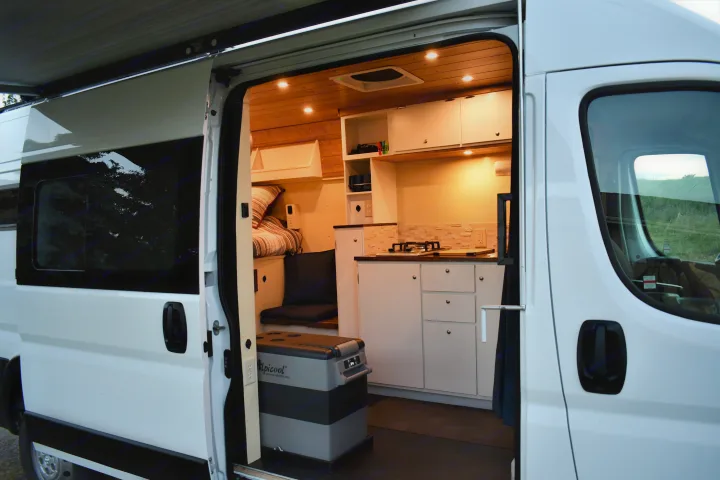Explore this cozy RV rental's custom van conversion: illuminated kitchen, bed, and fridge, perfect for road trips.. Other Other 2021