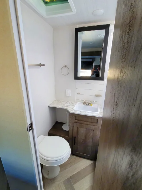 Clean RV rental bathroom with toilet, sink, mirror & modern vanity. Ideal for travel comfort.. Forest River Salem 2021