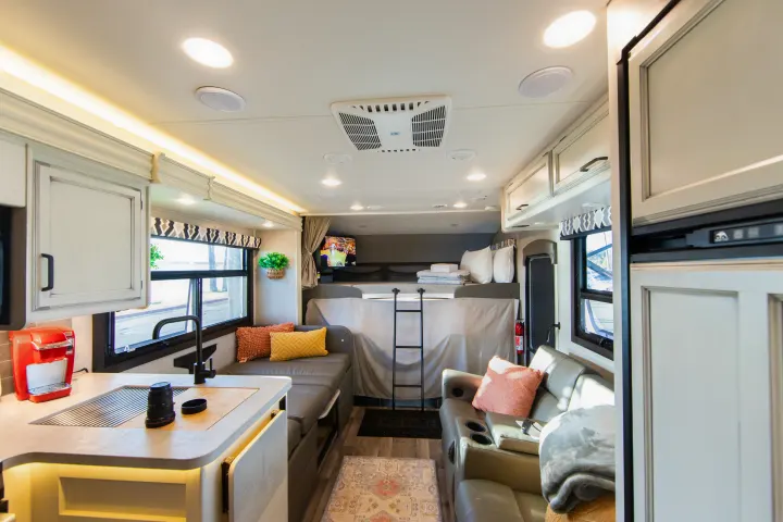 Spacious and modern RV rental interior featuring a cozy living area, full kitchen, and comfortable bunk bed with TV.. Jayco Greyhawk 2021