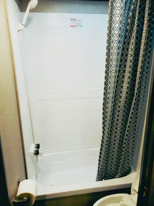 Inside an RV rental: a compact bathroom with a bright white tub/shower combo, shower curtain, and toilet for comfortable travel.. Jayco Jay Flight SLX 2021