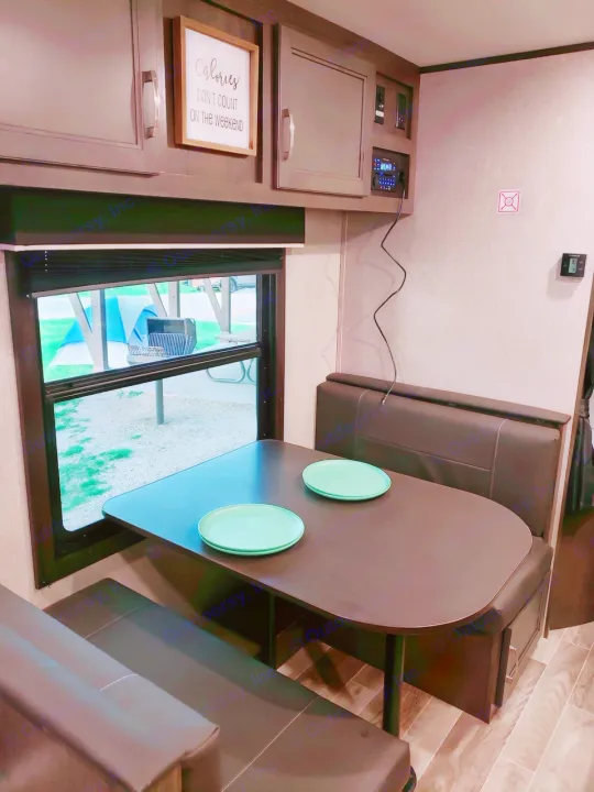 This RV rental features a cozy dinette with a dark wood table, two plates, and comfortable benches, ideal for travel.. Jayco Jay Flight SLX 2021