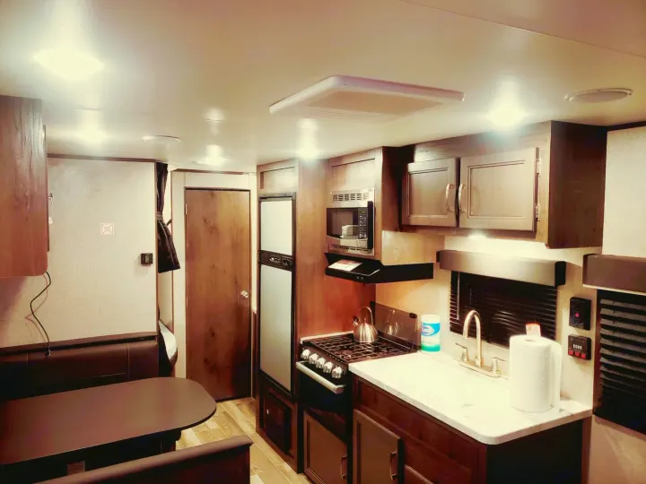 Clean RV rental interior: kitchen with stove, sink, microwave, fridge, plus a dining booth.. Jayco Jay Flight SLX 2021