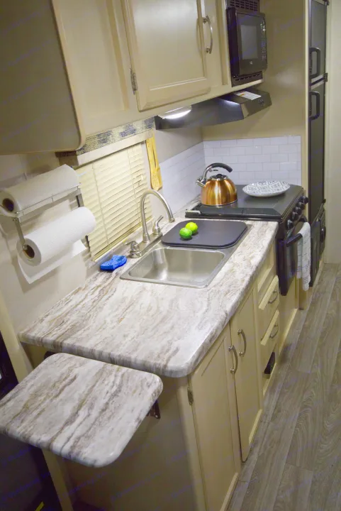 This RV rental kitchen boasts marbled countertops, a sink, stove, microwave, and storage, perfect for on-the-road cooking.. Other Other 2019
