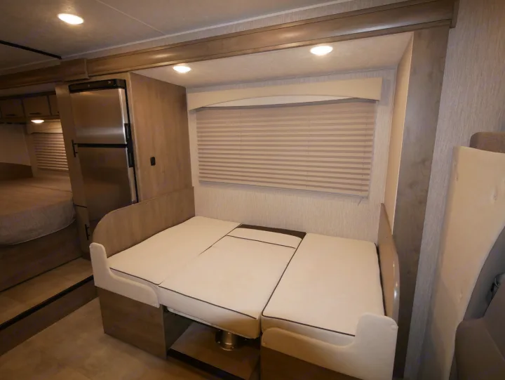 RV rental interior showcases a convertible dinette bed, integrated fridge, and back bedroom. Compact, functional travel living.. Coachmen Freelander 23FS 2022