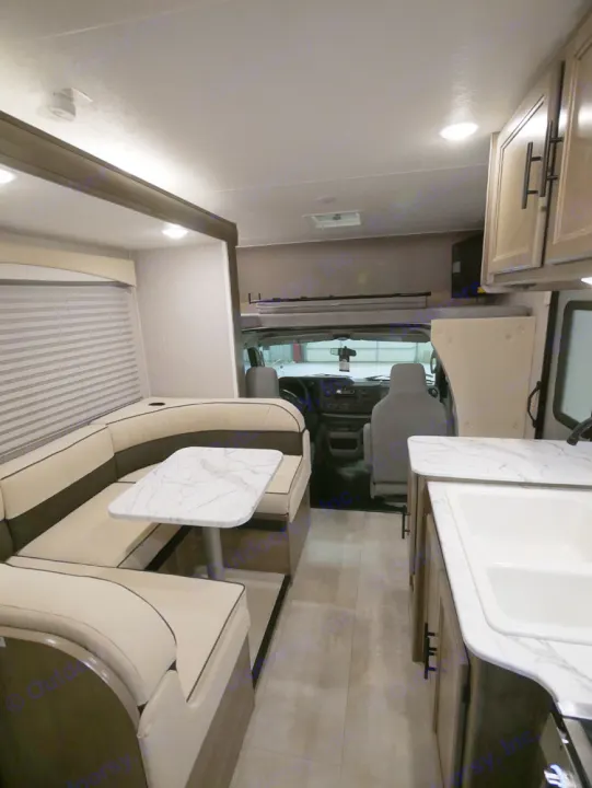 RV rental interior: modern U-shaped dinette, kitchen with marble-look counter & sink, driver's cab.. Coachmen Freelander 23FS 2022