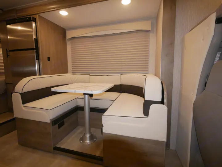 RV rental's U-shaped dinette & table setup; includes fridge, ideal for compact RV living.. Coachmen Freelander 23FS 2022