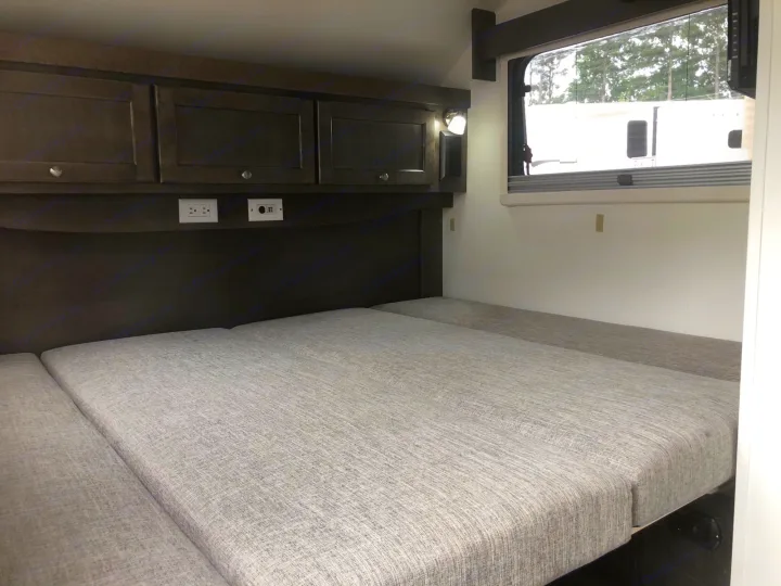 This RV rental features a cozy sleeping area with gray cushions, overhead storage, outlets, and a window.. T@B T@B 320 OffRoad 2020