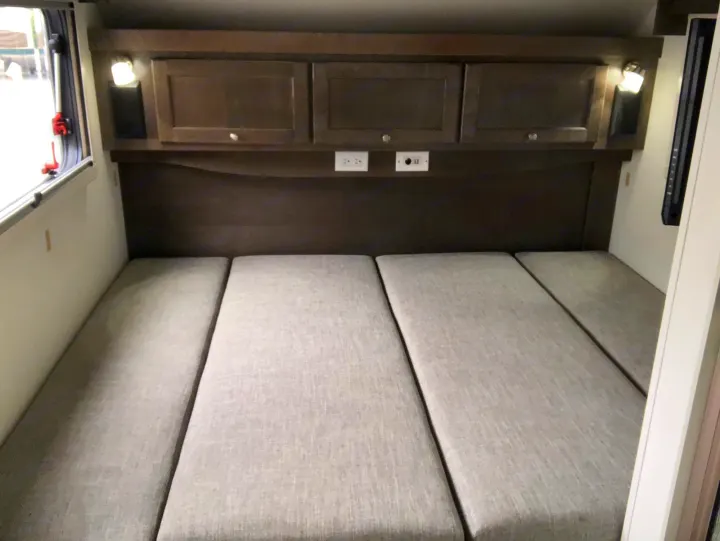 Inside an RV rental: a flexible sleeping area with modular cushions, overhead cabinets, bedside lights, and power outlets.. T@B T@B 320 OffRoad 2020