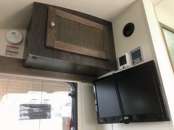RV rental interior: A dark wood cabinet, smoke detector, dual TVs, and digital controls create a compact, functional space.. T@B T@B 320 OffRoad 2020