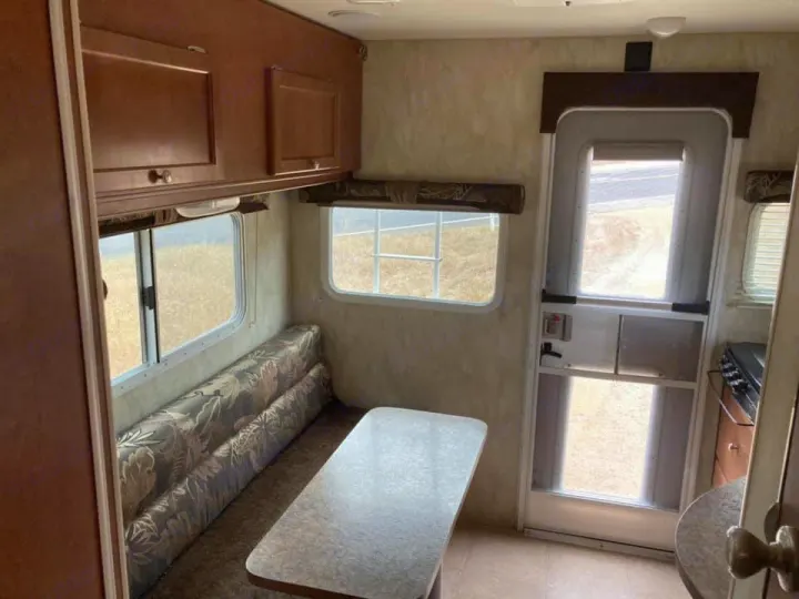 Spacious RV rental interior featuring a dinette, overhead cabinets, and bright windows. Ideal for travel adventures.. Northwood Mfg Wolf Creek 2017