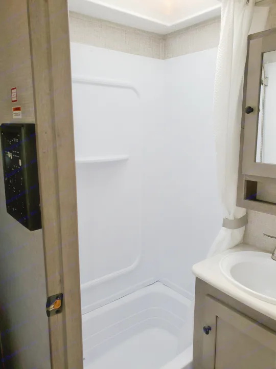 Clean and compact RV rental bathroom with shower, sink, and vanity for comfortable travel.. Keystone Outback 2020