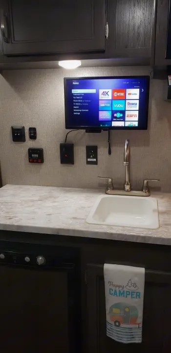 RV rental kitchen: a bright counter with sink & faucet, wall-mounted Roku TV, and essential camper controls.. Jayco Jay Flight 2021