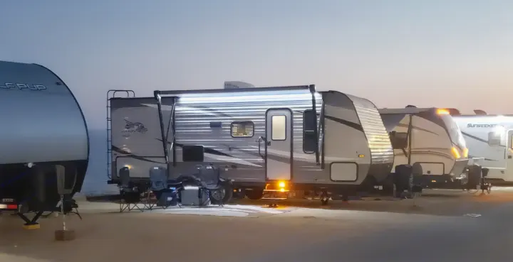 Multiple illuminated travel trailers at a tranquil evening RV campsite. Perfect for an rv rental adventure.. Jayco Jayflight 224bhw 2021