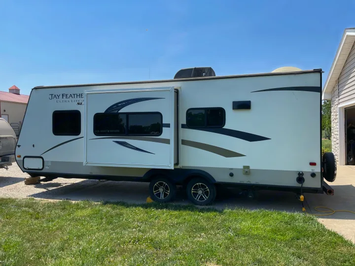 White Jay Feather travel trailer RV, slide-out extended & plugged in. Ideal for your next rv rental trip on a clear day.. Jayco Jay Feather Ultra Lite 2015