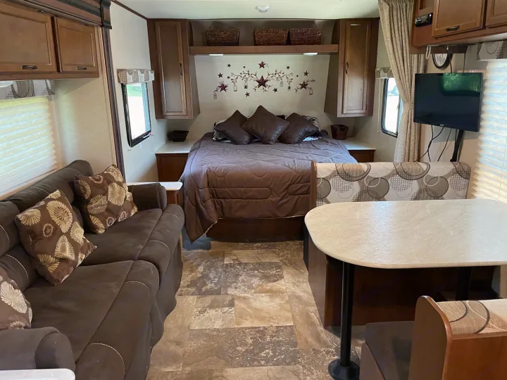 Cozy and functional RV interior with a full bed, sofa, and dinette. Perfect setup for your next rv rental adventure!. Jayco Jay Feather Ultra Lite 2015
