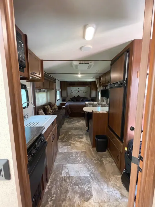 Spacious rv rental interior featuring a kitchen, dinette, living area with sofa, and comfortable bedroom. Your perfect mobile home.. Jayco Jay Feather Ultra Lite 2015