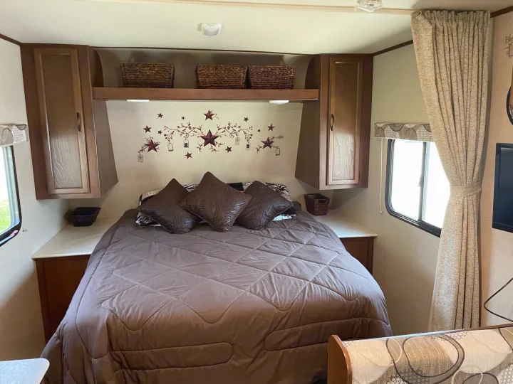 RV rental bedroom: cozy space with bed, overhead storage, and rustic star wall decor.. Jayco Jay Feather Ultra Lite 2015
