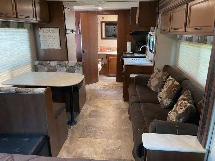 Inside an rv rental: Cozy dinette, functional kitchen, and plush sofa offer comfort. A hallway leads to the bathroom.. Jayco Jay Feather Ultra Lite 2015