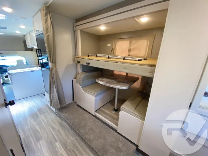 This RV rental interior features cozy bunk beds with a dinette, offering comfortable living space for your adventure.. Thor Motor Coach Four Winds 2021