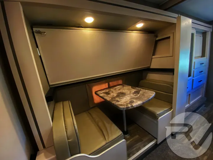 Cozy RV rental dinette with table, seating, and a fold-down bunk, perfect for compact travel.. Thor Motor Coach Four Winds 2021