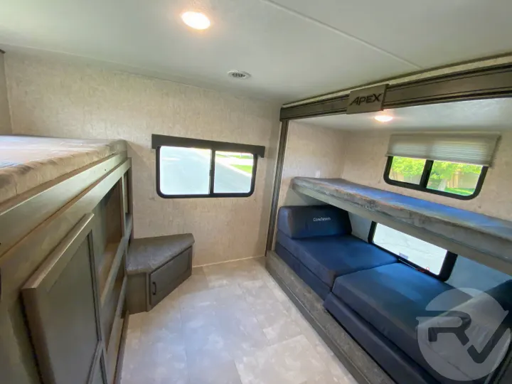 RV rental bunkhouse area with two sets of bunk beds, one with storage. Includes windows & a Coachmen convertible sofa.. Coachmen Apex 2021