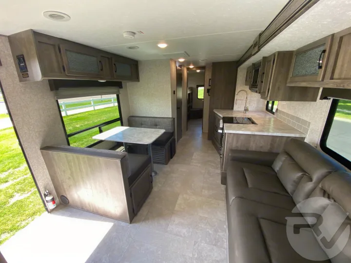 Spacious RV rental interior with a cozy dinette, well-equipped kitchen, and comfortable lounge area. Ideal for family trips.. Coachmen Apex 2021