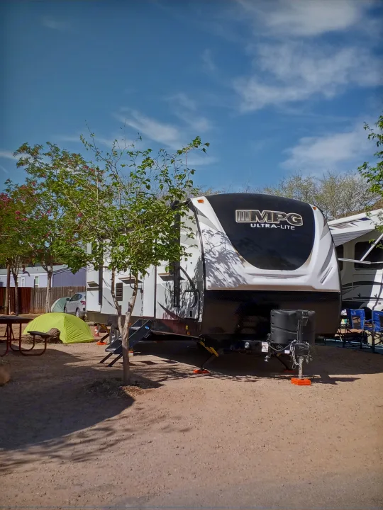 Sunny rv rental campsite featuring an MPG Ultra-Lite travel trailer, a small green tent, and a picnic table.. Cruiser RV MPG Ultra Lite 2021