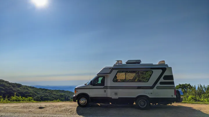 Scenic RV rental adventure: A white Chinook camper van parked with stunning mountain views under a bright sky. Perfect for road trips!. Chinook Concourse 2001