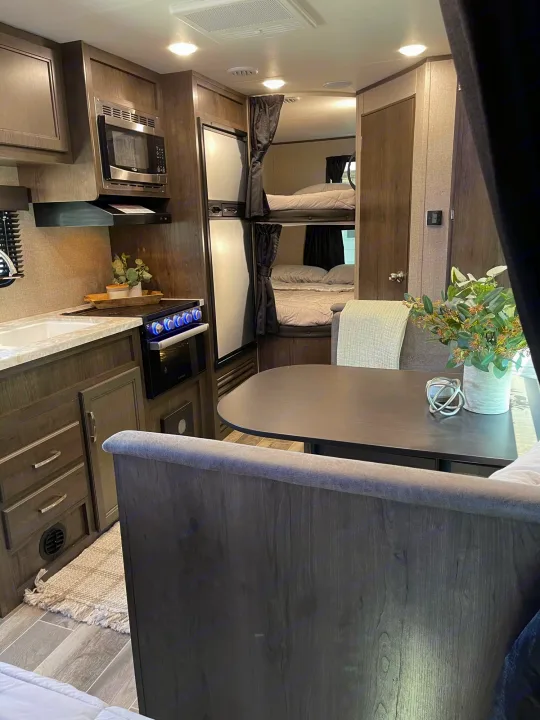 This RV rental interior features a full kitchen, dining area, and cozy bunk beds, offering a comfortable travel experience.. Jayco Jayflight 224bhw 2021
