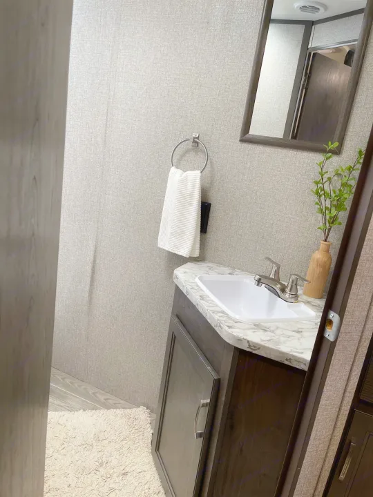This RV rental bathroom features a compact vanity with a sink, marble-patterned counter, mirror, and white towel.. Jayco Jayflight 224bhw 2021