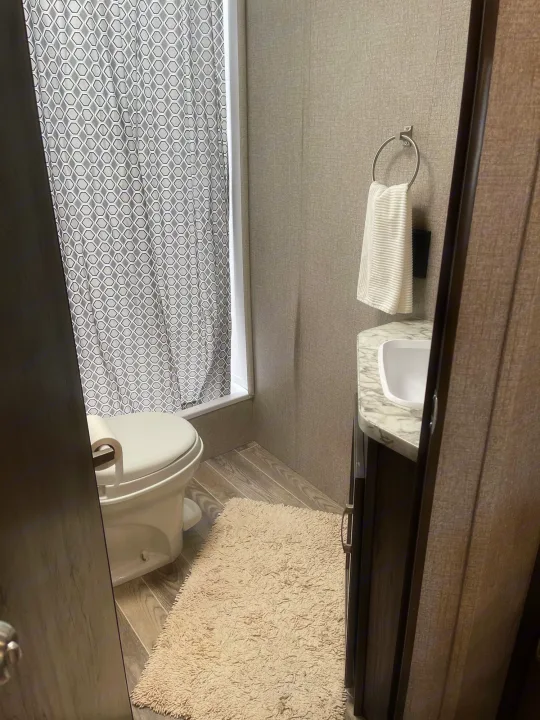 Clean RV rental bathroom with toilet, shower, sink, and bath mat. Compact and modern amenities for your trip.. Jayco Jayflight 224bhw 2021