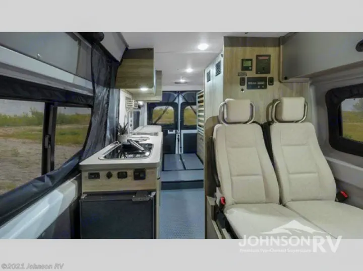 This rv rental features a compact kitchen with a sink, stove, and integrated fridge, alongside two comfortable passenger seats.. Winnebago Solis 2022