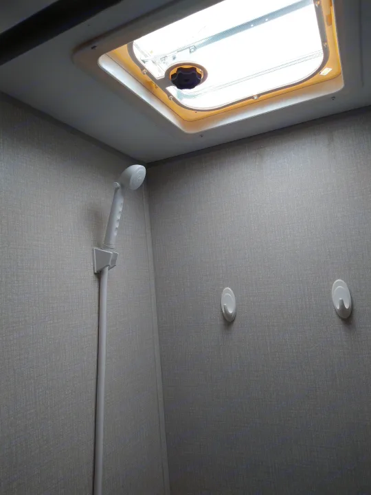 Compact RV rental bathroom featuring a window, handheld shower, and ceiling lights, ideal for small spaces.. KZ 181BH 2021