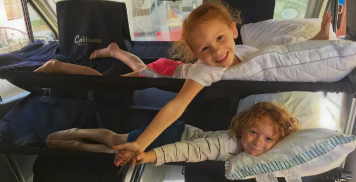 Two children smile, comfy on Cabbunk bunk beds in an RV rental. Great compact sleeping for family adventures.. Other Sprinter 2016