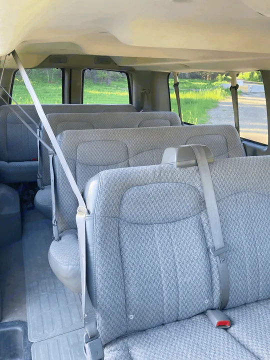 Interior of an RV rental: multiple rows of grey patterned cloth seats, with visible seatbelts, ready for a road trip.. Chevrolet Express 2007