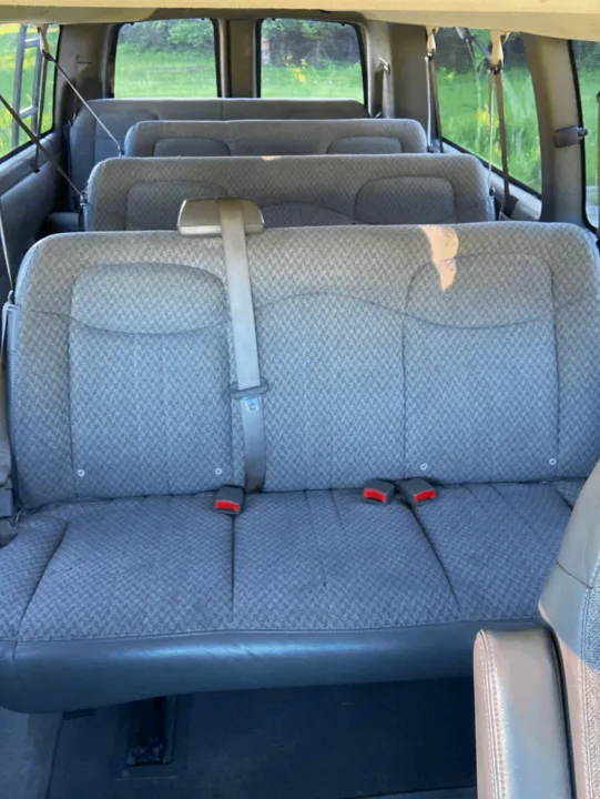 Spacious RV rental interior with three rows of grey passenger seats, perfect for family adventures & group travel.. Chevrolet Express 2007