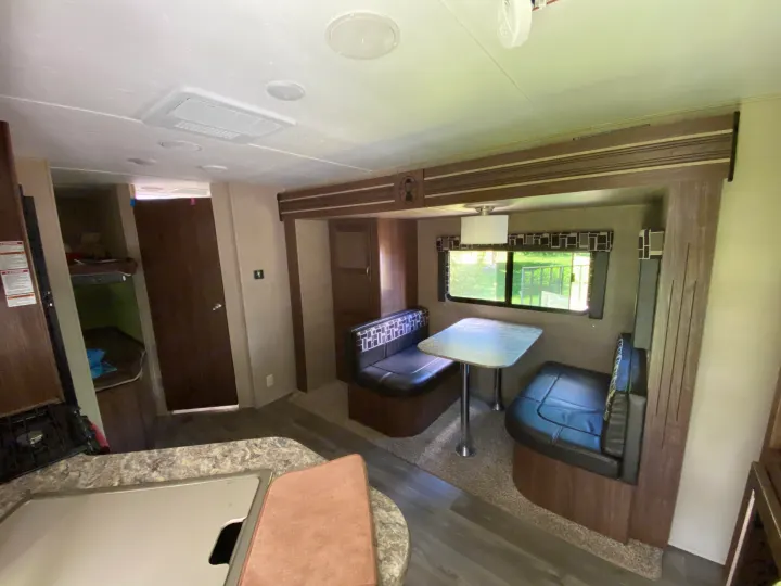 Inside a cozy rv rental: dinette, kitchen counter with sink, and a glimpse of the bunk area, ideal for travel.. Coleman Light 2405BH 2017