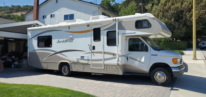 White and gray Fleetwood Jamboree Class C RV (Ford E-450) parked on a paved driveway, ideal for an rv rental.. Fleetwood Jamboree 2006