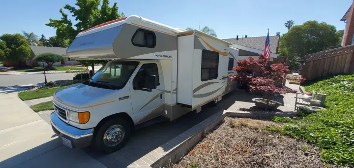 Sunny view of a white and gray Fleetwood Class C RV in a residential driveway, ideal for your next rv rental trip.. Fleetwood Jamboree 2006
