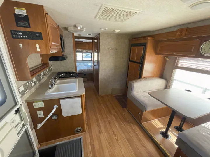 Spacious RV rental interior featuring a kitchenette, dinette, and bedroom area. Perfect for your next adventure.. Fleetwood Jamboree 2006