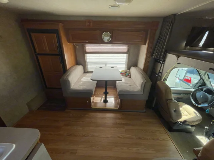 Explore this inviting RV rental interior, featuring a dinette, kitchenette, and driver's area with wood flooring.. Fleetwood Jamboree 2006