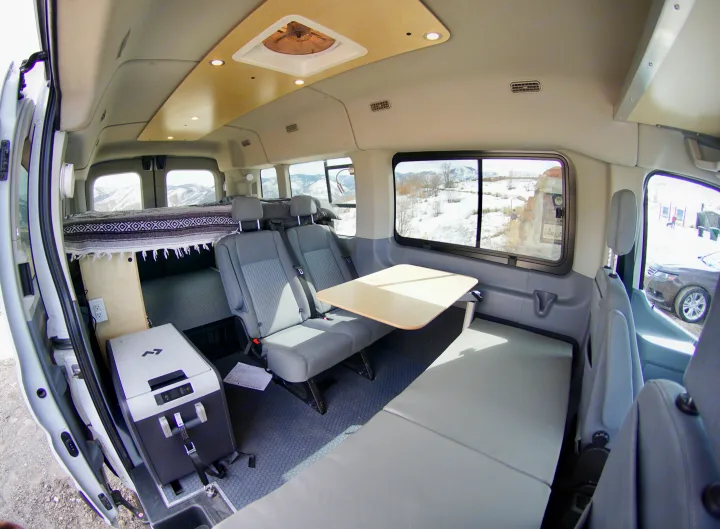Spacious RV rental camper van interior with bed, bench seating, table, and fridge for mobile living adventures.. Ford Transit Custom 2019