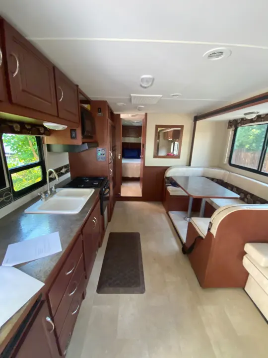Spacious RV rental interior featuring a full kitchen, dinette, and cozy bedroom. Perfect for travel adventures!. Winnebago Minnie Winnie 2015