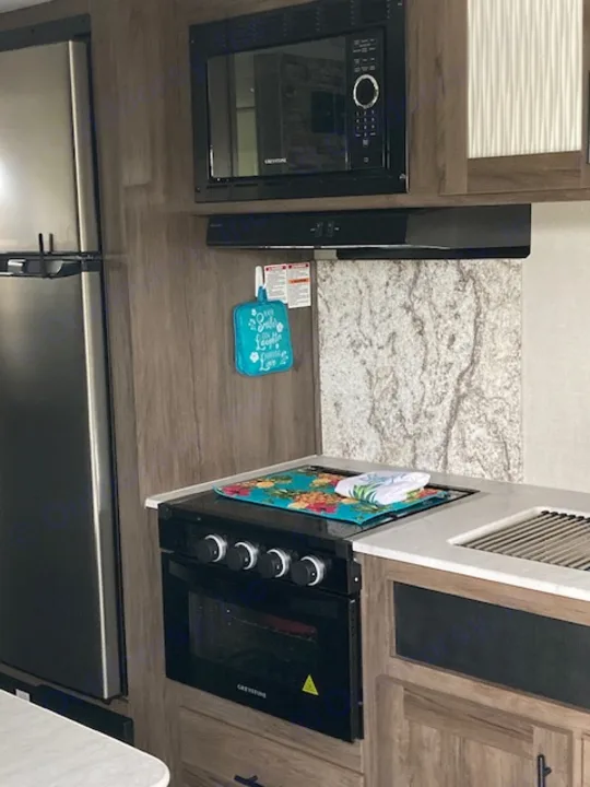 RV rental kitchen showing microwave, range, refrigerator, & counter space. Ready for your travels!. Forest River Prime Time Avenger 2021