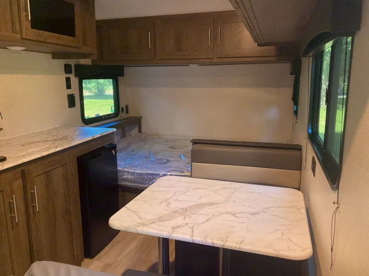 RV rental: Interior view of a compact living space featuring a white marble-patterned counter, dining table, and bed.. Other 1906st Saga 2021