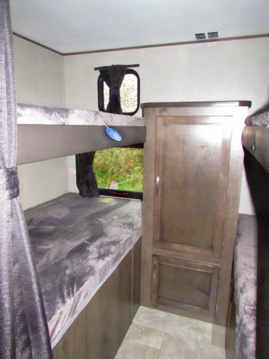 RV rental bunk room features upper & lower bunks with grey mattresses, a storage cabinet, and windows with outdoor views.. Jayco Jay Flight SLX 2021