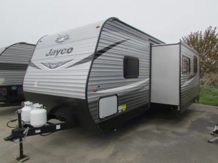 Gray Jayco travel trailer RV rental with slide-out extended, parked on asphalt.. Jayco Jay Flight SLX 2021