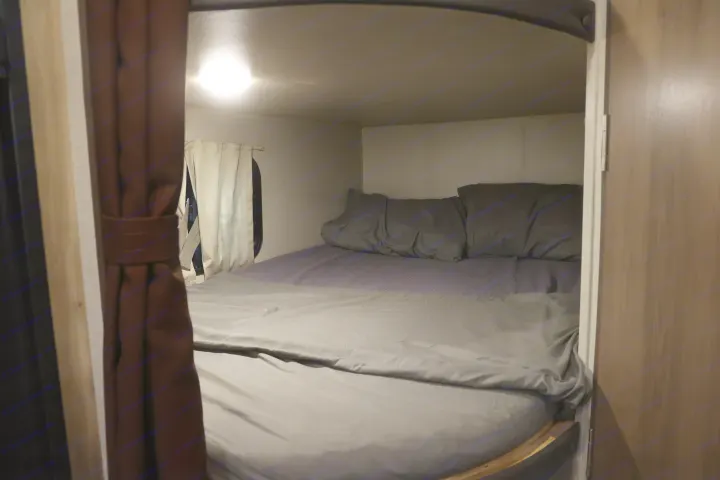 Cozy RV rental bedroom nook with comfy bed, pillows, and ambient light, ideal for travel.. Coachmen Catalina 2021