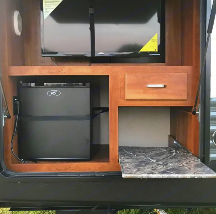 RV rental outdoor setup: TV, mini-fridge, drawer, and pull-out counter for convenient exterior use.. Keystone Summerland 2017